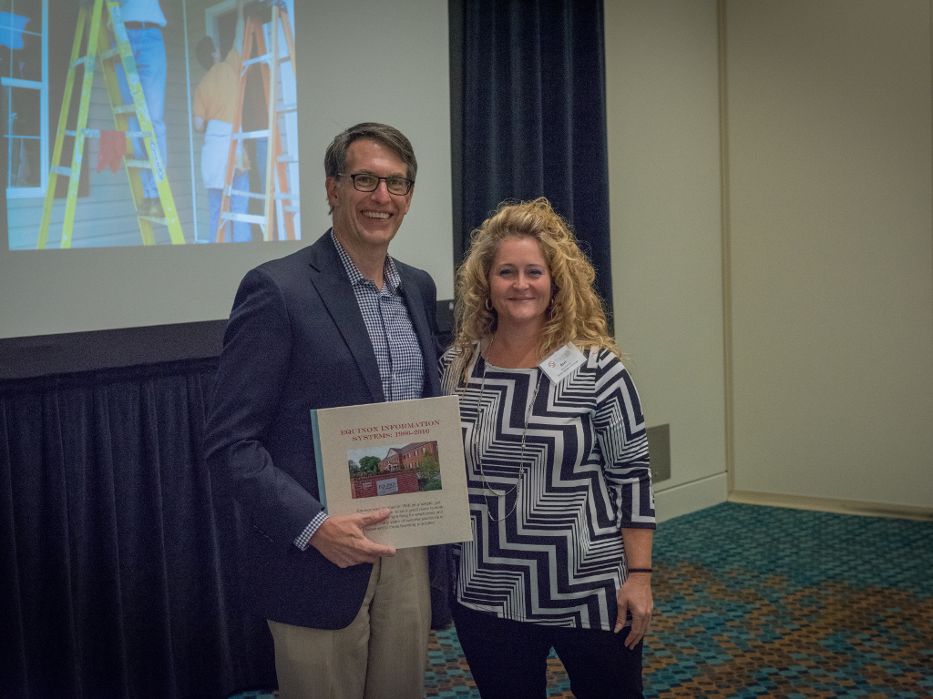 Byron is presented with a commemorative book for Equinox's 30th anniversary